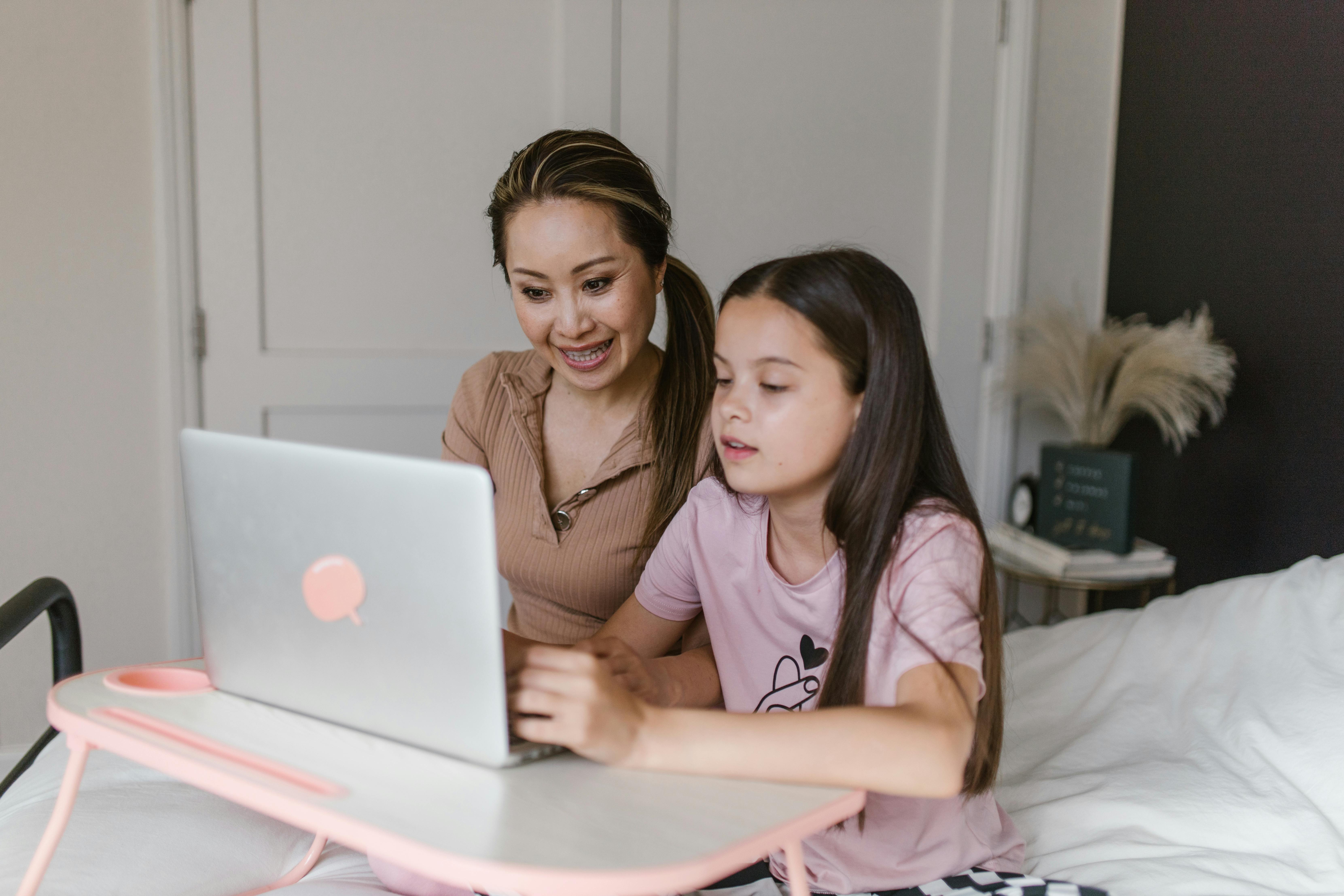 Woman helping girl with laptop